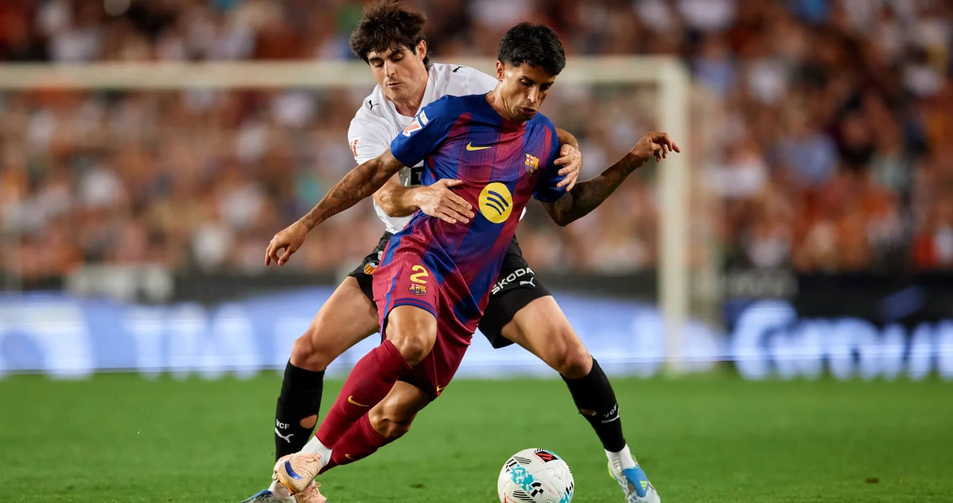 Barcelona player challenged by Valencia opponent during match Barcelona player challenged by Valencia opponent during match