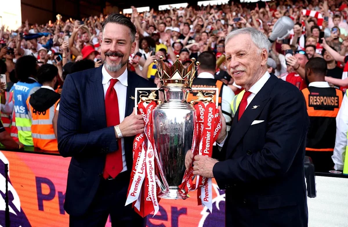 Two officials holding Premier League trophy with fans cheering Two officials holding Premier League trophy with fans cheering