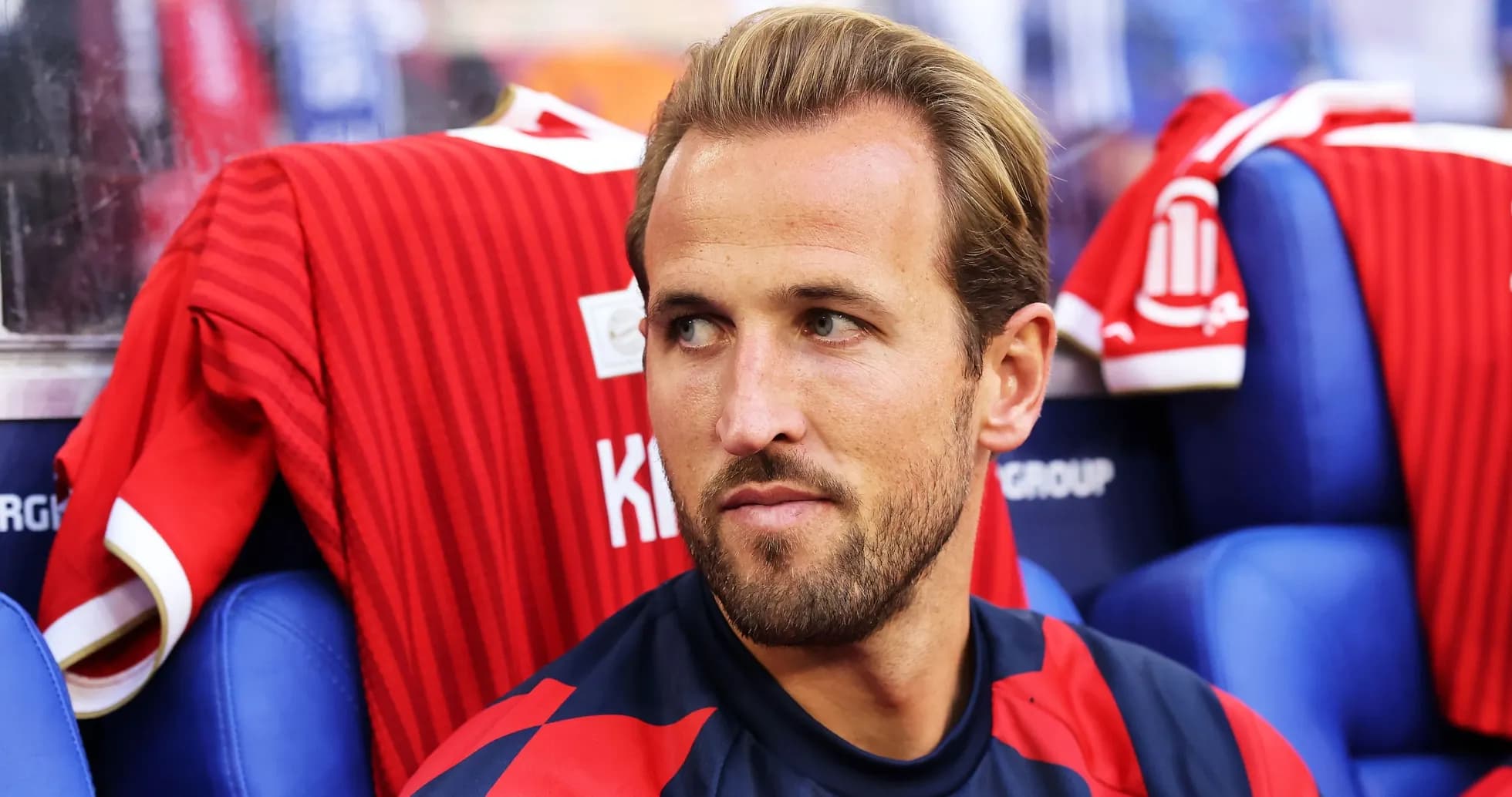 Player sitting on bench with red jersey behind Player sitting on bench with red jersey behind