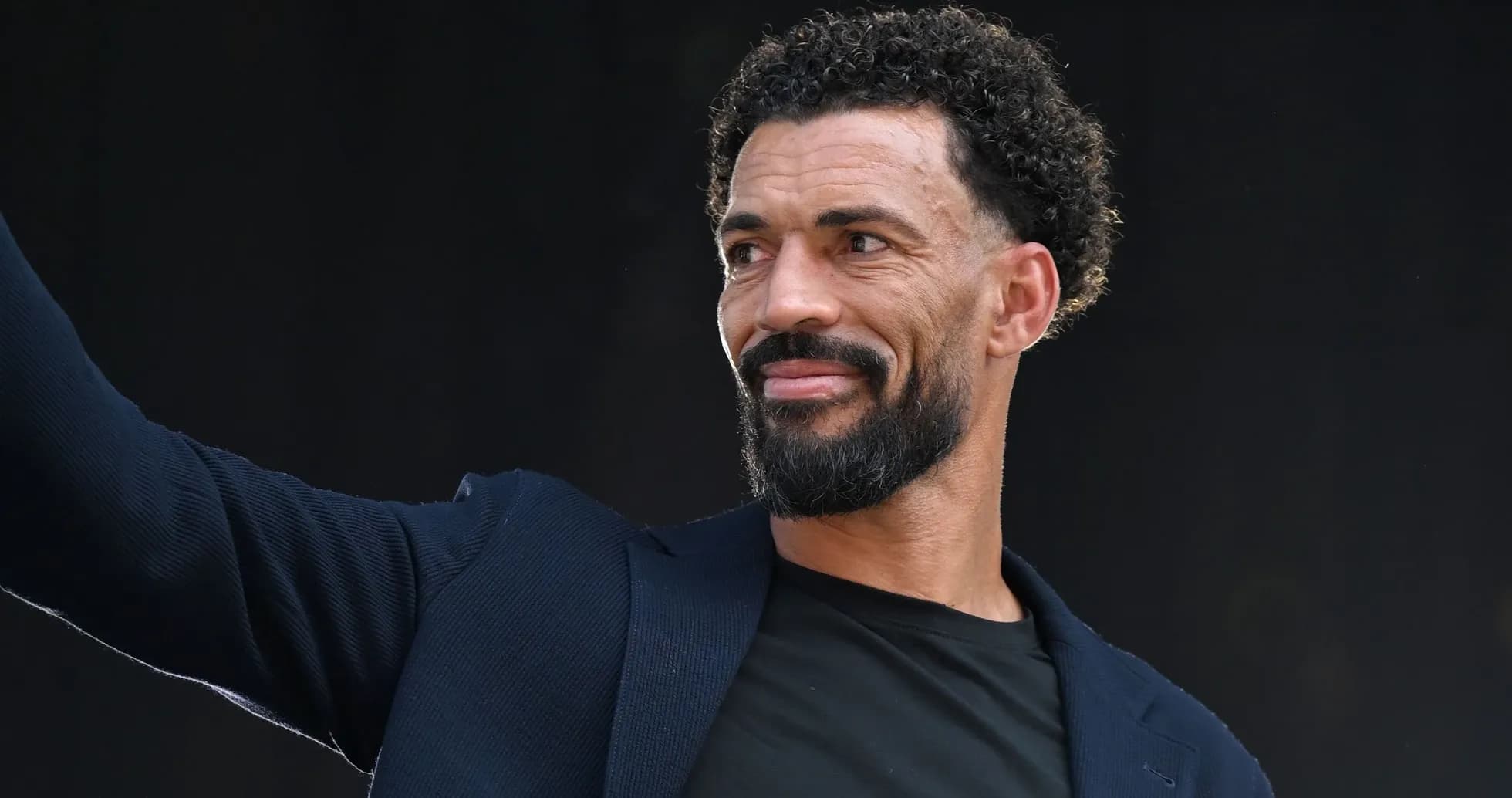 Man in suit waving at an event Man in suit waving at an event