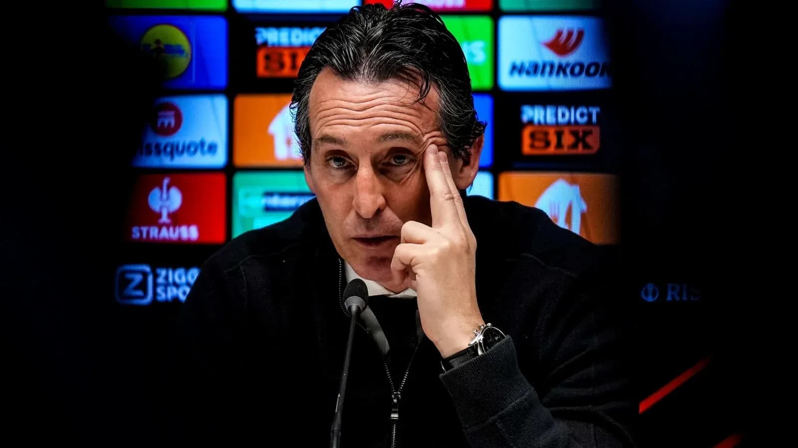 Manager speaking at press conference with logos behind Manager speaking at press conference with logos behind