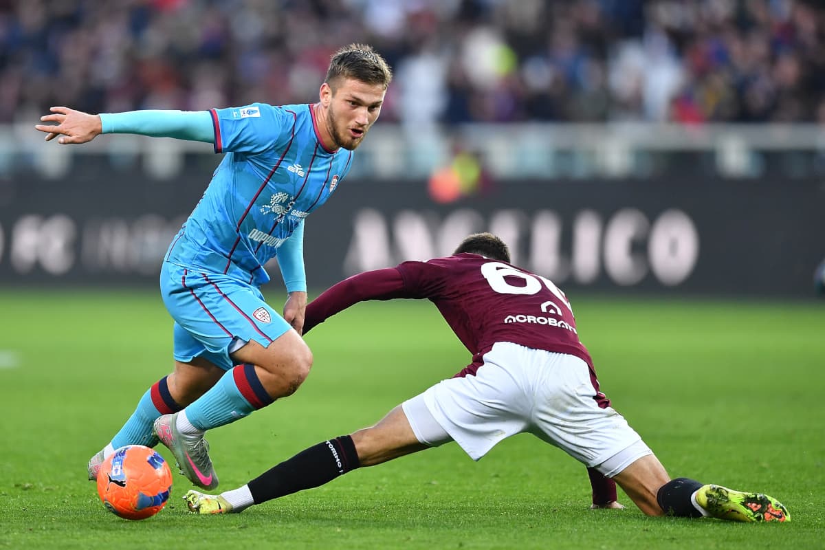 Cagliari player evading Torino tackle during match Cagliari player evading Torino tackle during match