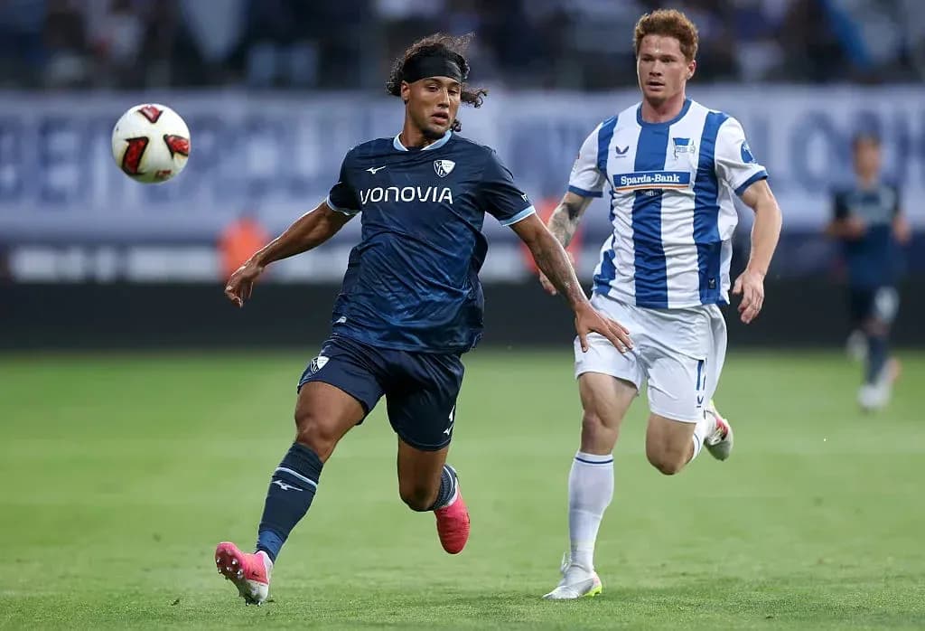 Player in dark kit dribbling past opponent in light kit Player in dark kit dribbling past opponent in light kit