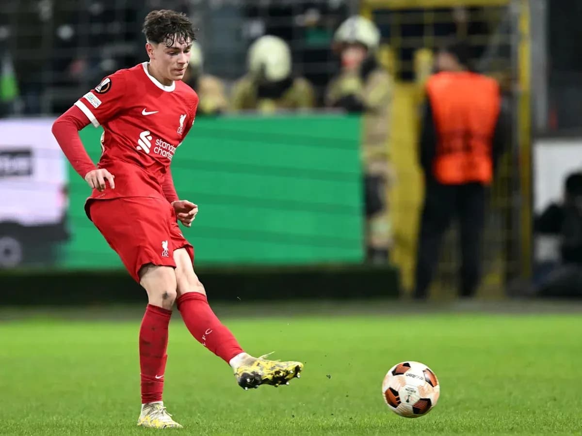 Player in red kicking a soccer ball on field Player in red kicking a soccer ball on field