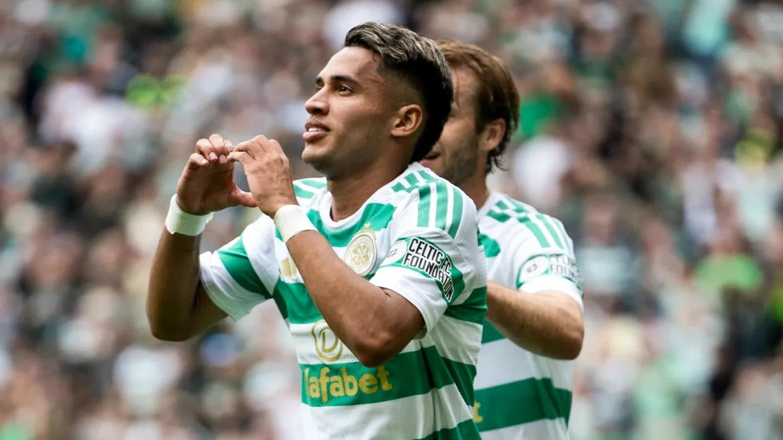 Player celebrating goal with heart gesture on pitch Player celebrating goal with heart gesture on pitch
