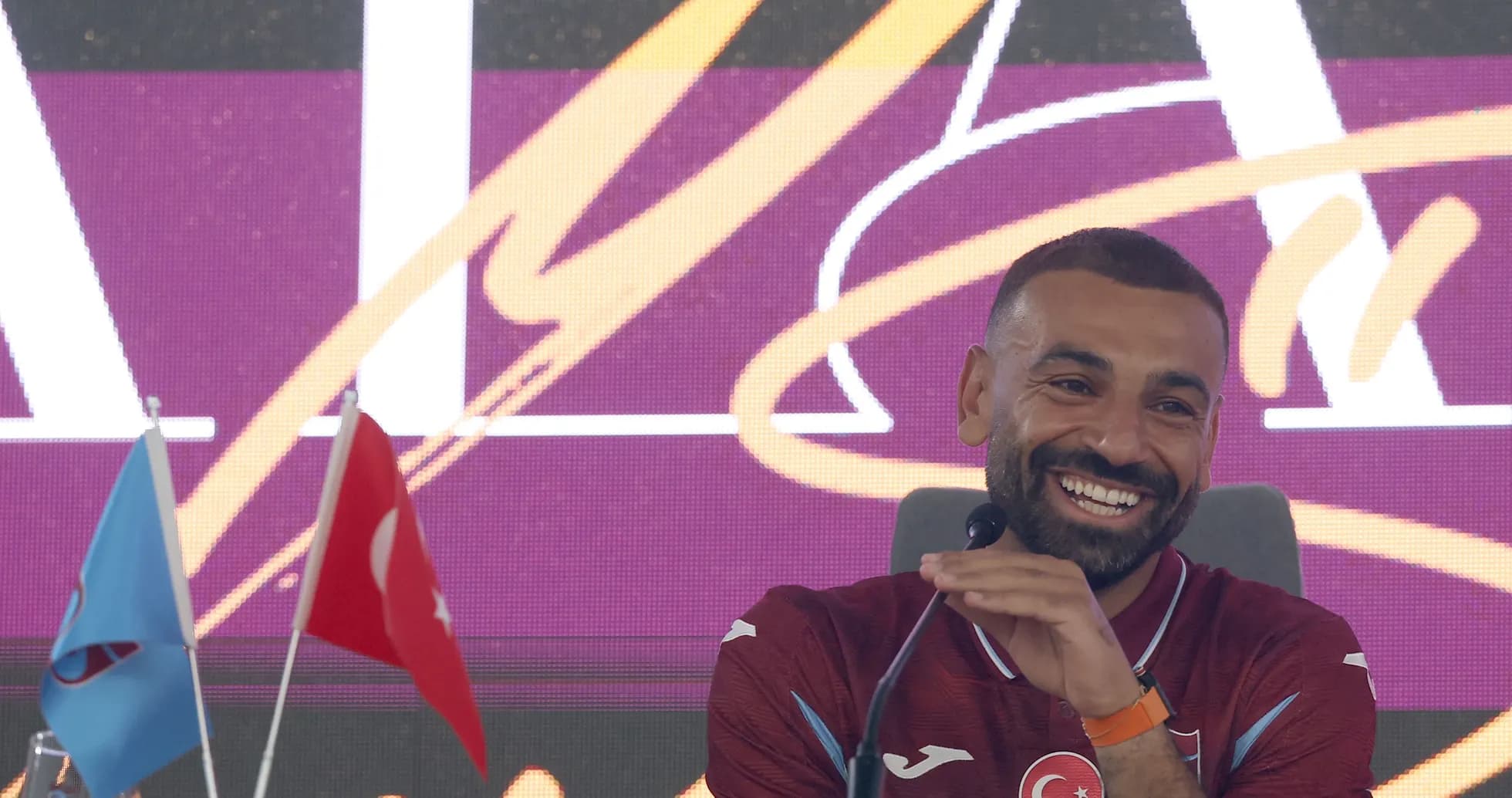 Player smiling at press conference with flags Player smiling at press conference with flags