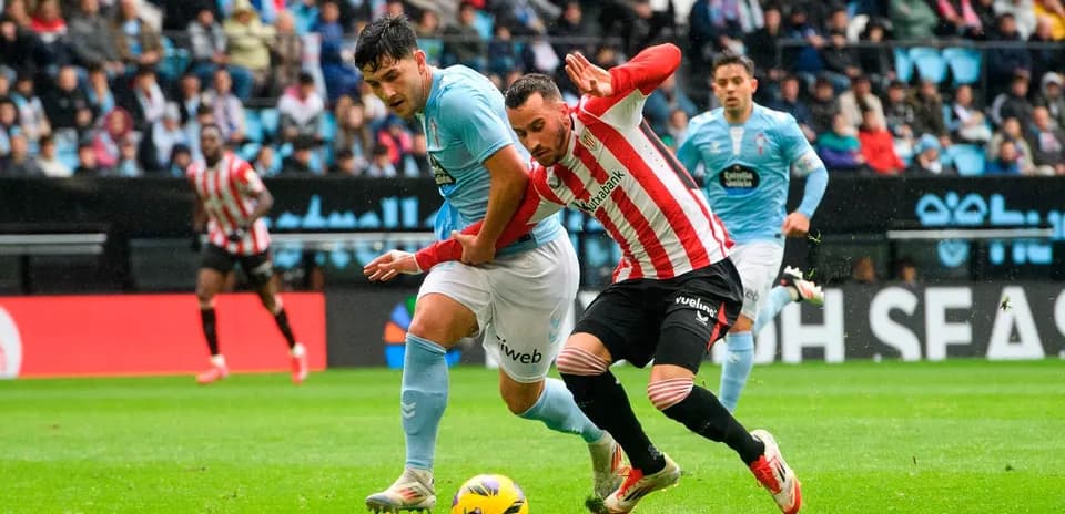 Athletic Club player tackling Celta Vigo opponent Athletic Club player tackling Celta Vigo opponent