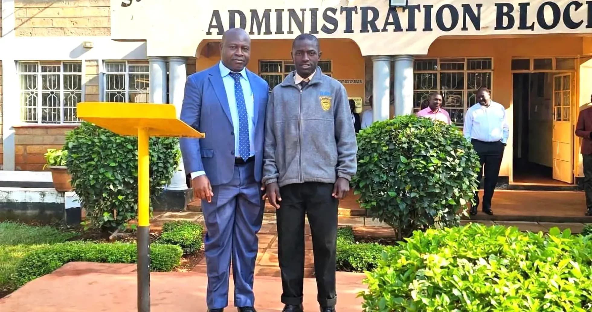 Two men posing in front of school building Two men posing in front of school building