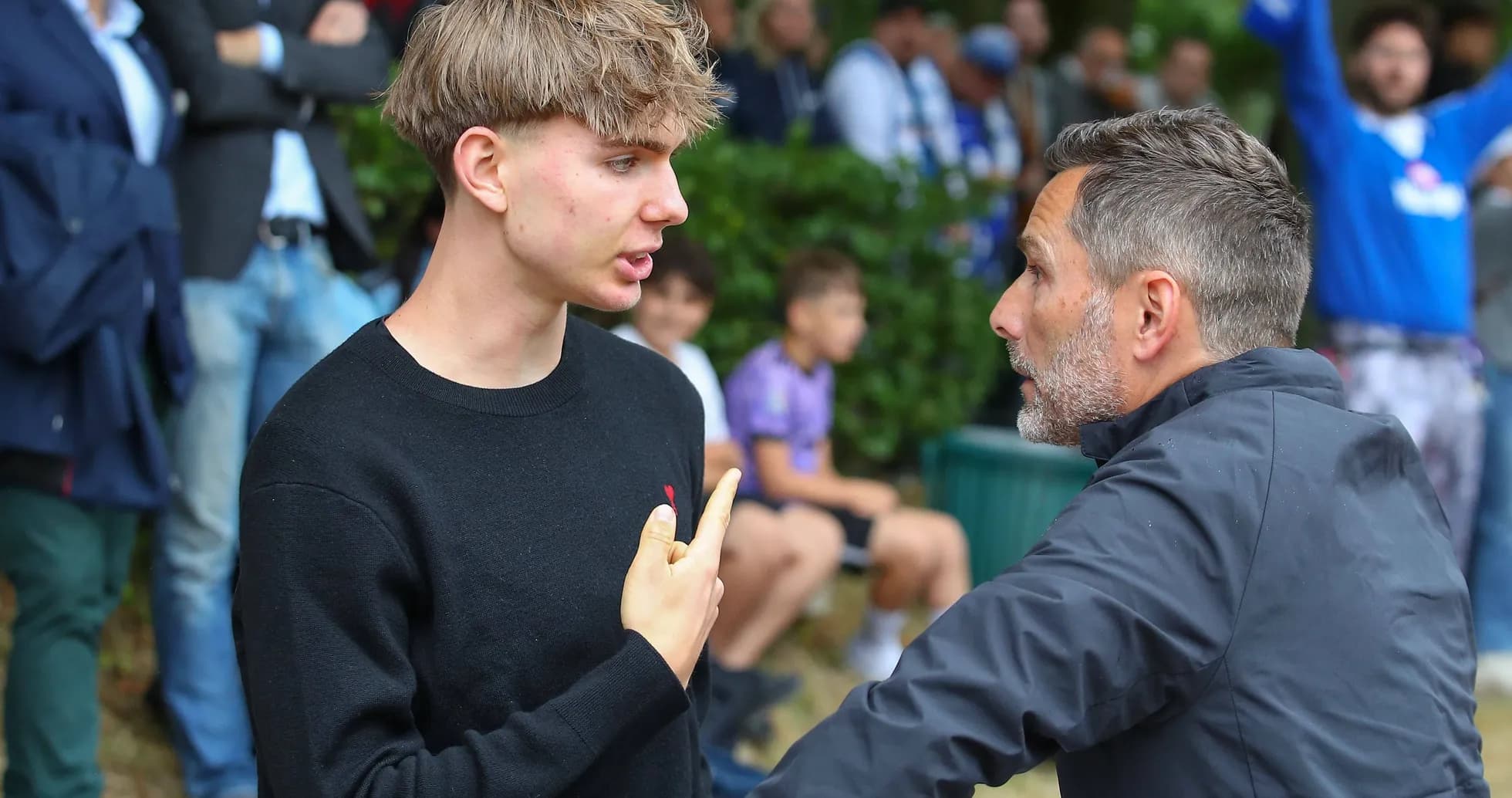 Two men discussing intently near a crowd Two men discussing intently near a crowd