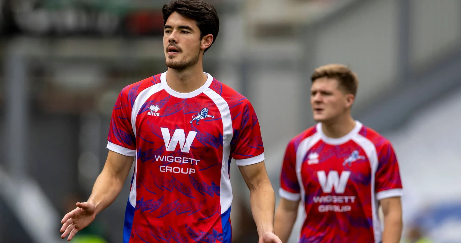 Players in red and blue jerseys walking on pitch Players in red and blue jerseys walking on pitch