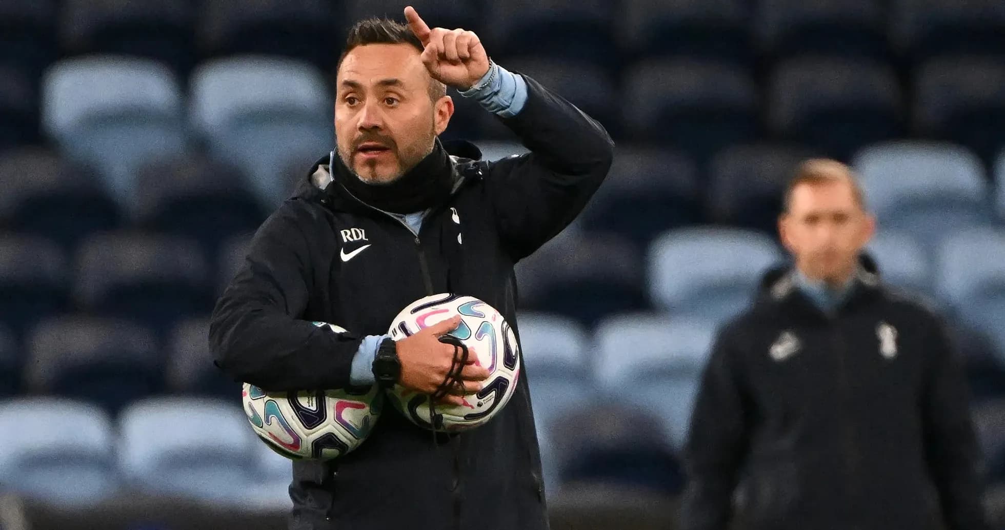 Coach instructing players while holding footballs Coach instructing players while holding footballs