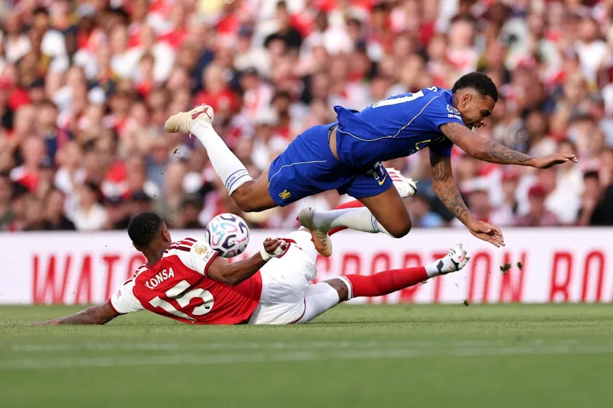 Player from Chelsea jumping over fallen Arsenal player Player from Chelsea jumping over fallen Arsenal player