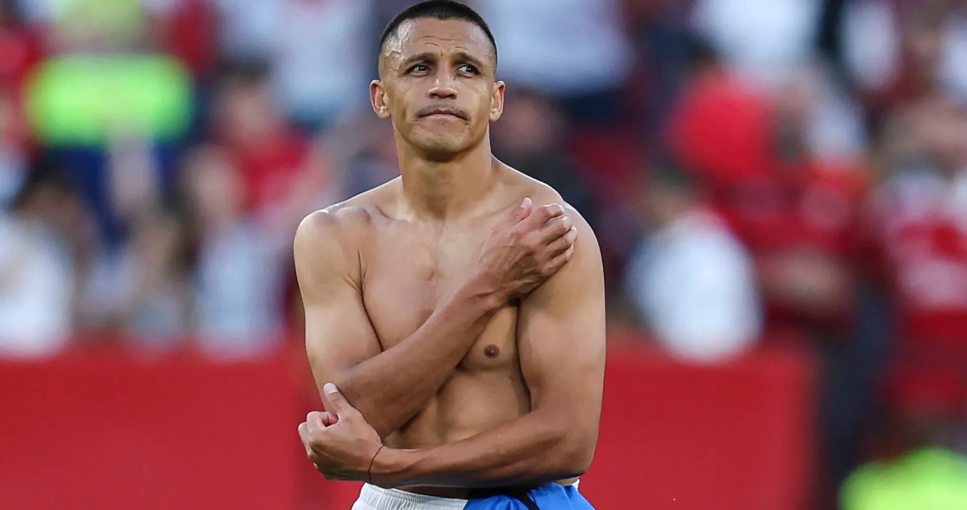 Player with shirt off, holding shoulder on field Player with shirt off, holding shoulder on field