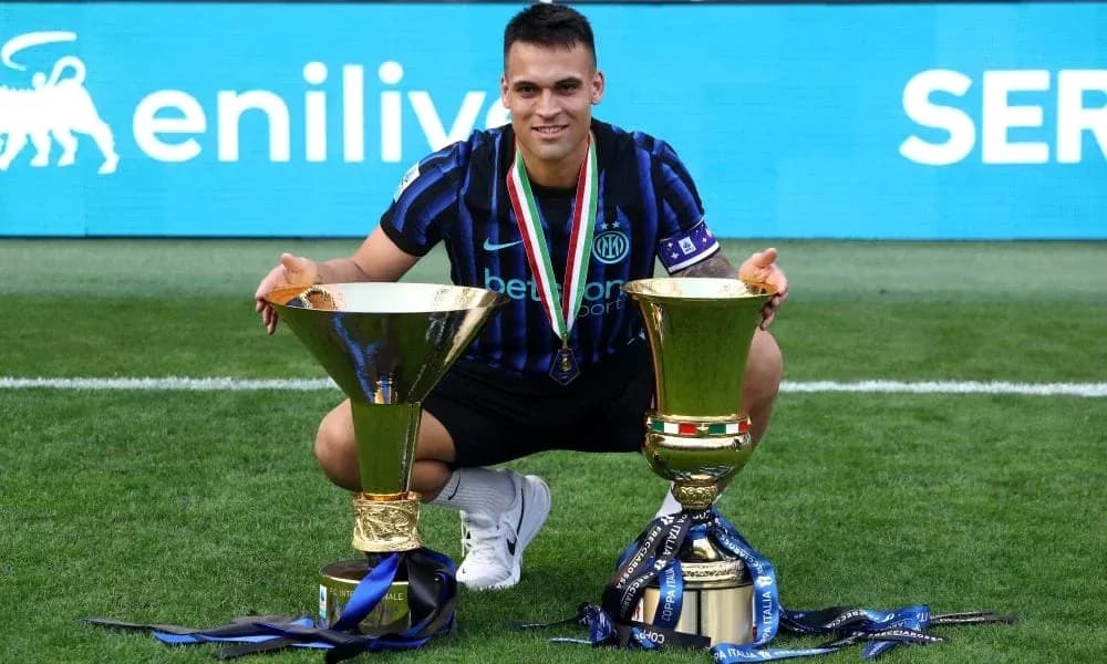 Player celebrating with two trophies on the field Player celebrating with two trophies on the field