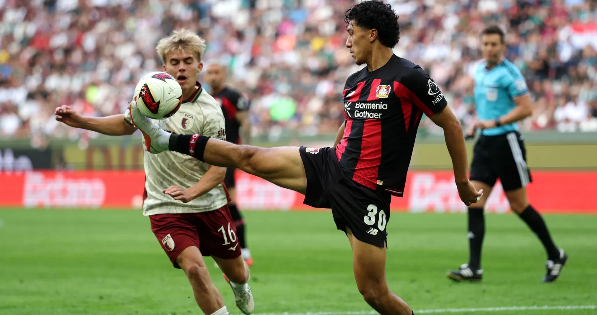 Player kicking ball while another player approaches Player kicking ball while another player approaches