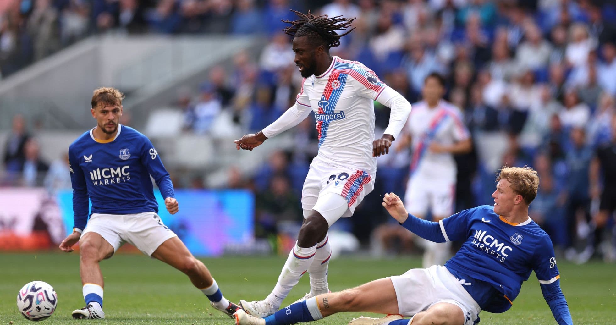 Player in white dribbling past two opponents in blue Player in white dribbling past two opponents in blue